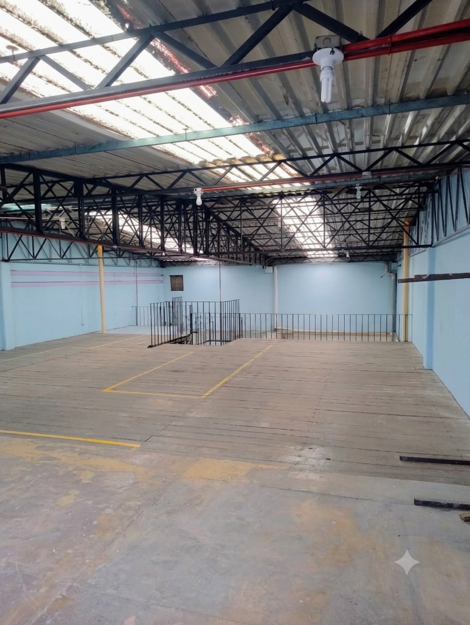 Nave industrial con estructura metálica, muros azul claro y andenes con rejas