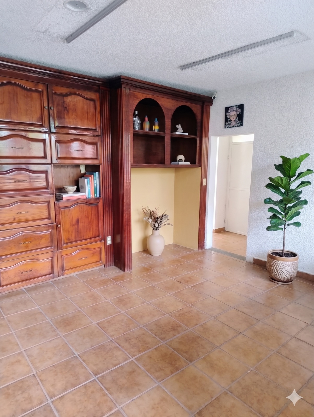 Oficina con libreros y alacenas de madera empotrados y piso de barro